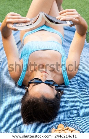 girl reading a book while sunbathing in a bikini in her garden