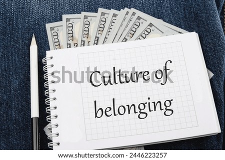 Culture of belonging symbol on a notebook lying on jeans with dollar bills
