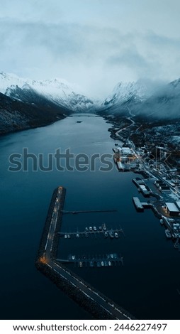 Aerial Drone of Gryllefjord in Lofoten, Norway.  A small fishing village in the Arctic Circle of Northern Norway during the winter months with snow capped peaks and mountains.