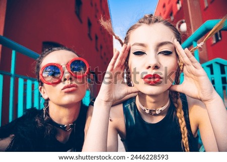 Lifestyle selfie portrait of two young women having fun and making selfie, Caucasian girls posing on city street. Portrait of two friends with bright makeup and stylish hairstyles with pigtails