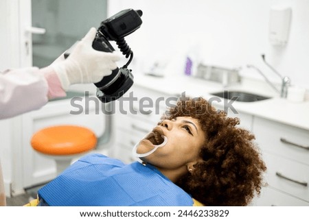 A dark-skinned woman visits a dentist. An unrecognizable dentist takes a photograph of the mouth of a woman with Arab features. Dental photography concept.