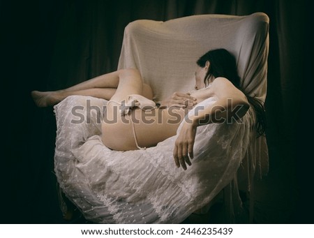 woman without clothes lying in an armchair on lace and tulle with a cuttlefish on her body, in a romantic attitude in the style of baroque paintings with chiaroscuro Royalty-Free Stock Photo #2446235439