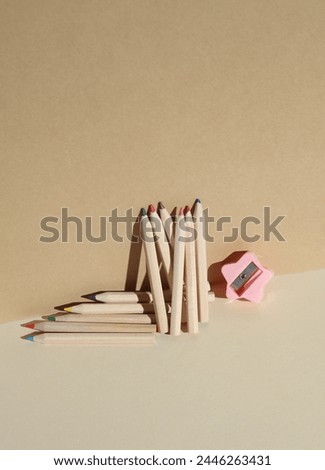 Set of wooden colored pencils and sharpener on a beige background with shadow