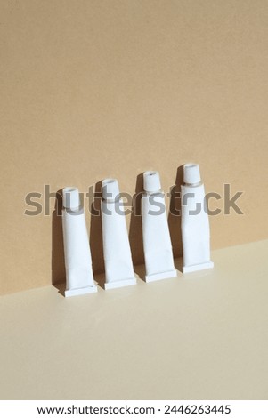 White tubes of acrylic or oil paint on a beige background. Mockup for design