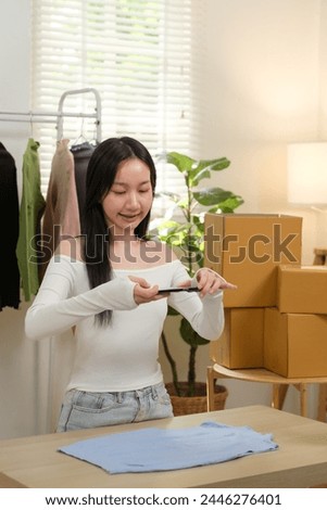 Young business woman takes a photo of a cloth with her smartphone device to put it up for sale on a second-hand clothing platform. online selling concept