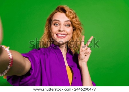 Photo portrait of pretty young girl take selfie show v-sign wear trendy purple outfit isolated on green color background