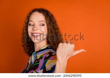 Photo of lovely pretty cheerful girl wear trendy print clothes demonstrate look empty space isolated on vivid orange color background