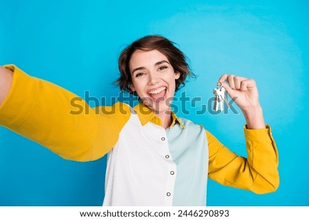 Selfie photo young woman working realtor recording video lots keys of apartments in residential complex isolated on blue color background
