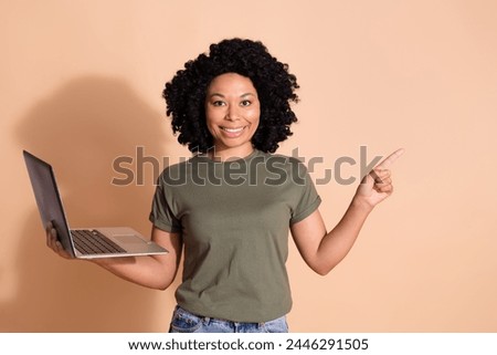 Photo of multiethnic multinational woman wear khaki t-shirt hold laptop indicaitng at sale empty space isolated on pastel color background Royalty-Free Stock Photo #2446291505