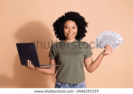 Photo of rich cheerful woman with perming coiffure wear khaki t-shirt hold laptop win money in casino isolated on pastel color background