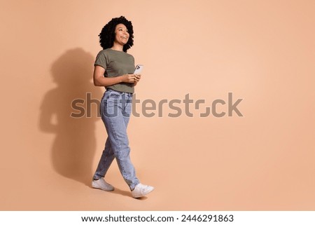 Full size photo of cheerful person wear khaki t-shirt look at sale empty space hold smartphone isolated on pastel color background