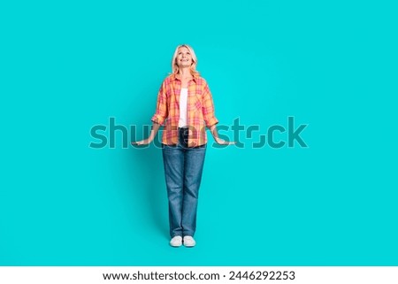 Full length photo of good mood woman dressed plaid shirt denim pants look up at sale empty space isolated on turquoise color background