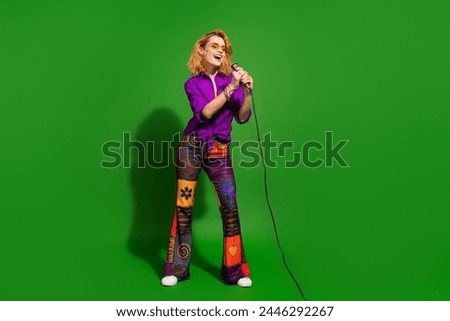 Photo portrait of lovely young lady singing hold microphone dressed stylish violet clothes isolated on green color background
