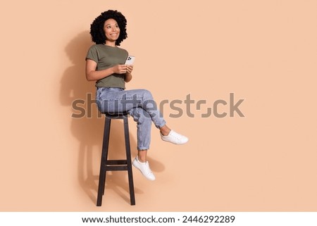 Full size photo of dreamy person wear khaki t-shirt on chair hold smartphone look at offer empty space isolated on pastel color background