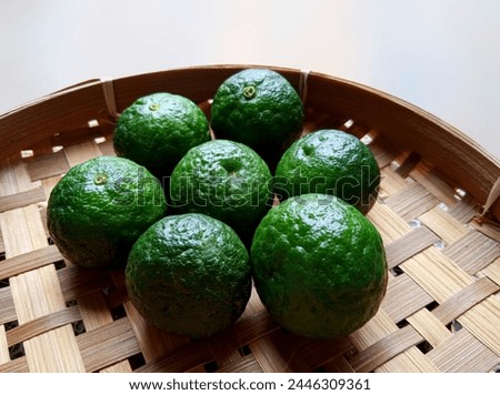 13. Seven green limes (Citrus xamblicarpa), placed on a woven bamboo plate (13) Royalty-Free Stock Photo #2446309361