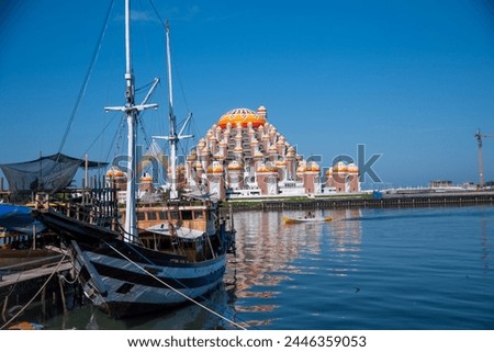 Phinisi wooden boats anchor at Losari Beach. Famous traditional boat from Makassar. Masjid 99 Kubah (99 Domes Mosque) in the background 

