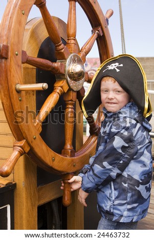 boy wearing pirate hat at ships wheel