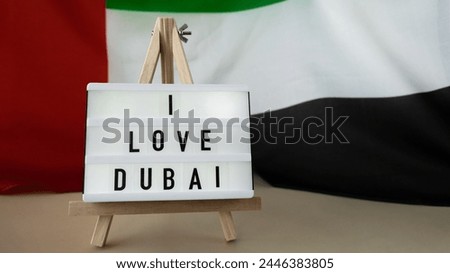 Message text I LOVE DUBAI on background of waving UAE flag made from silk. United Arab Emirates flag with concept of tourism and traveling. Inviting greeting card, advertisement