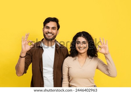 Happy Couple Showing Okay Sign Against Yellow Background - Positive Gesture, Relationship, and Satisfaction Concept Royalty-Free Stock Photo #2446402963