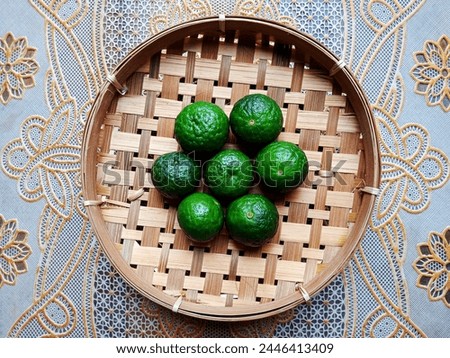 14. Seven green limes (Citrus xamblicarpa), placed on a woven bamboo plate (14) Royalty-Free Stock Photo #2446413409