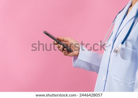 Using mobile phone Close up female medical doctor isolated on pink background.