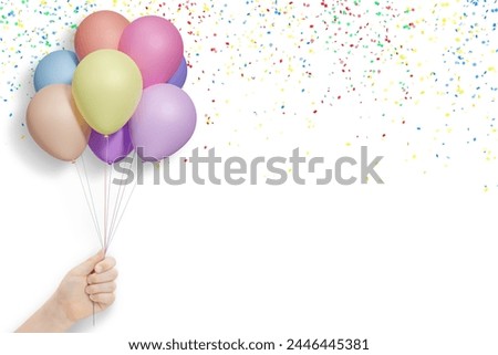 Female hand holds bunch of colorful balloons on white background with confetti. Empty space for text