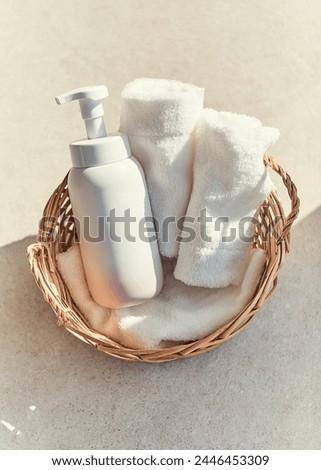 Two white towels and a white plastic container in a rattan basket on a table in a sunny bathroom
