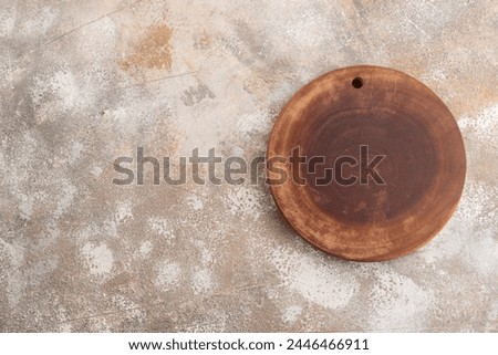 Empty round wooden cutting board on brown concrete background. Top view, copy space, flat lay.