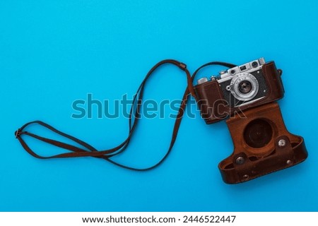 Retro camera in leather case on blue background