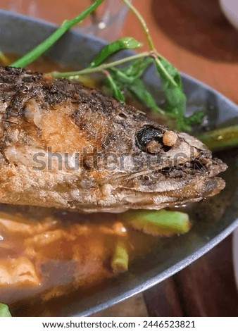 a photography of a fish in a bowl of broth and vegetables.