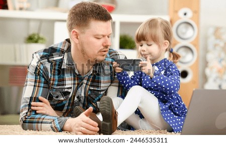 Cute little girl on floor carpet with dad use cellphone calling mom portrait. Life style apps social web network wireless ip telephony concept