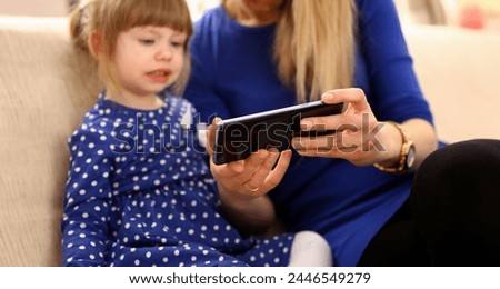 Cute little girl on floor carpet with mom use cellphone calling dad closeup. Life style apps social web network wireless ip telephony concept