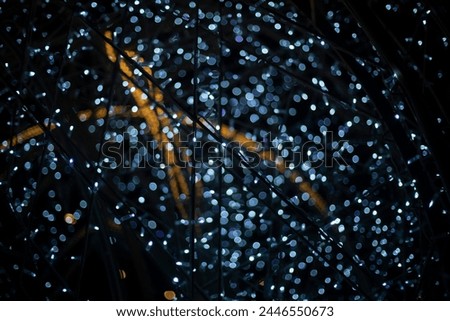 Garlands in dark. Bright light bulbs on black background. Decorating city during holidays. Lots of glowing garlands.