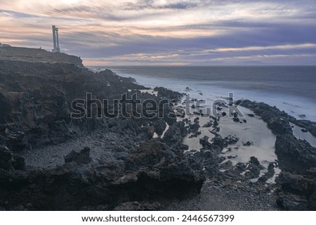 volcanic  landscape and ocean with the Buenavista lighthouse, with the last light of the day, just before nightfall, long exposure photography, Tenerife, Canary islands