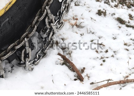 Tractor stands in a forest. Tractor's tire with chain that helps ride on ice and snow when sawing trees.