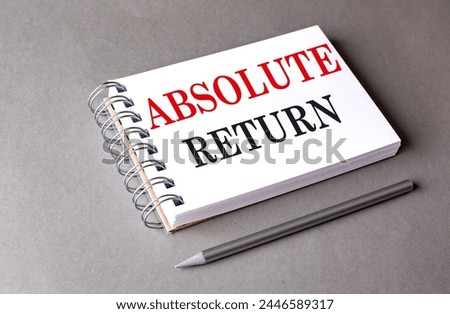ABSOLUTE RETURN text on a notebook on grey background 