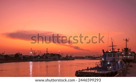 Silhouette many nautical vessels moored along the river bank at harbor against colorful orange sunset sky over sea in evening time Royalty-Free Stock Photo #2446599293