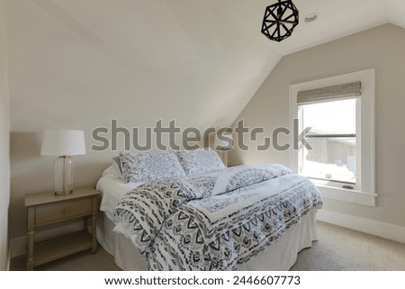 Sunlit bedroom with a cozy bed, twin lamps, and sunlight streaming through the window, creating a serene ambiance. Pictured in a traditional cottage.