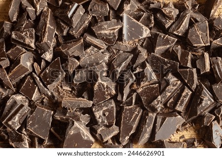 Overhead view of a sumptuous array of dark chocolate chunks. The glossy surfaces catch the light, revealing intricate textures and the deep, inviting hues of premium cocoa. Organic textures background Royalty-Free Stock Photo #2446626901