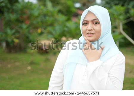 Portrait of an Asian female model wearing a blue hijab with various attractive facial expressions while out in nature during the day