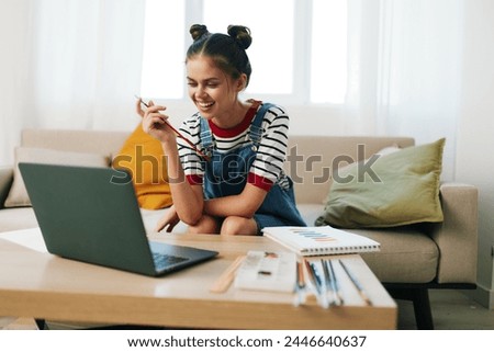 Happy Teenage Girl Painting Artwork on Laptop, Creating Colorful Portrait on Sofa in Modern Home Studio