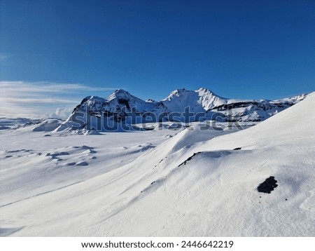 Snow plain with snowy mountains in the background