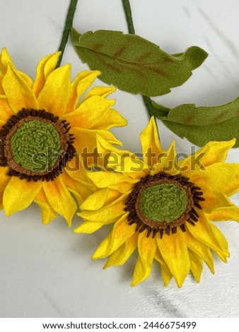 Sunflowers made out of felt fabrics are on a white marble background. They are fully handmade and used as home decorations. All parts were cut by free hand without any pattern or mold.