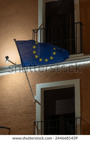 An European flag is hanging from a window on a building.