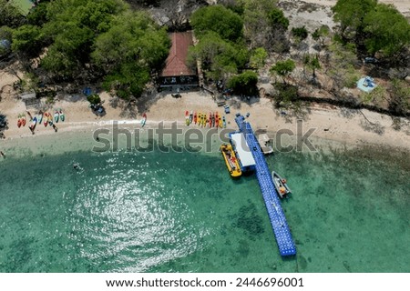 Surrounding Islands of Koh Kham, Thailand green lush tropical island in a blue and turquoise sea with islands in the background and clouds with sun beams shining through, drone aerial photo