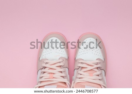 Top view of a pair of stylish white and pink sneakers on a pink background. Stylish sports shoes.