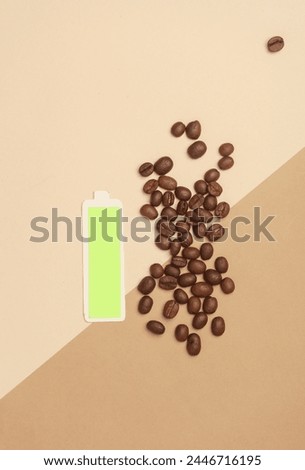 Coffee beans and fully charged battery on beige background Royalty-Free Stock Photo #2446716195
