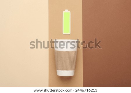 Cardboard coffee cup with a fully charged battery on a beige background. Charge of energy and strength for the whole day Royalty-Free Stock Photo #2446716213