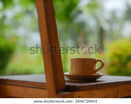 A ceramic cup and saucer sit on a wooden table outside.