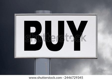 Close-up on a white billboard against a cloudy blue sky with the message "Buy" written in the middle.